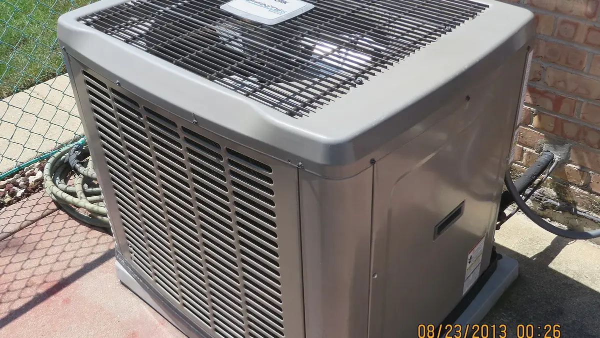 Outdoor condenser unit of a central air conditioning system next to a house