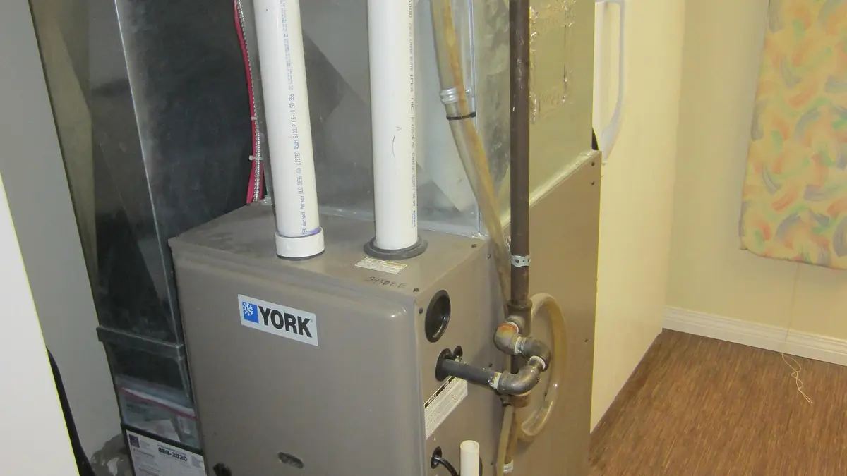 High-efficiency condensing gas furnace with white PVC vent and drain pipes