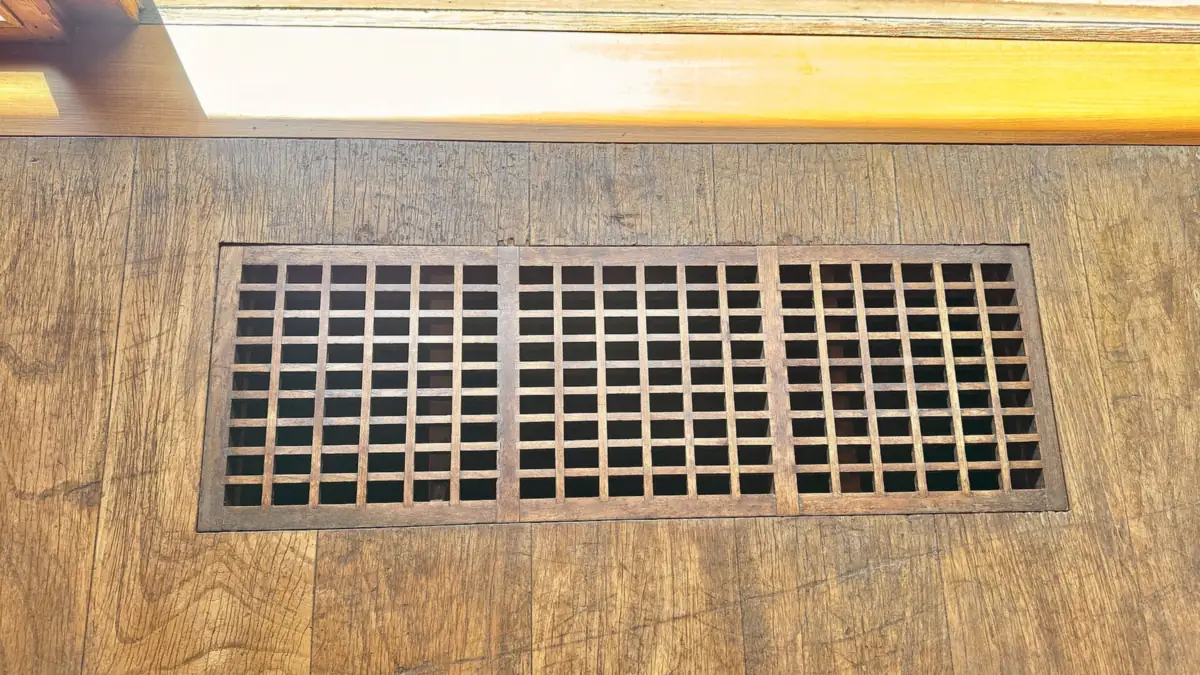 Metal heating and cooling register set in a hallway floor