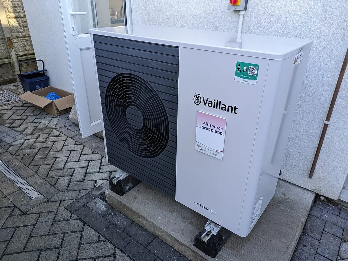 Air source heat pump outdoor unit on a wall bracket beside a terraced house