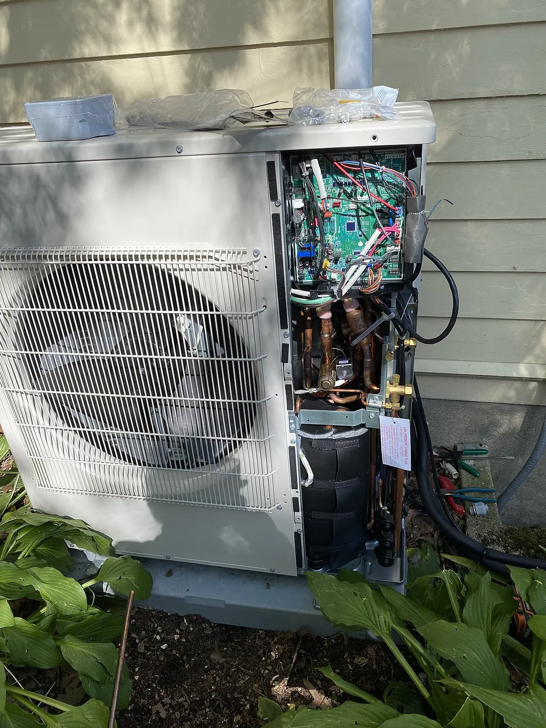 Open outdoor heat pump unit showing the compressor and copper refrigerant tubing inside
