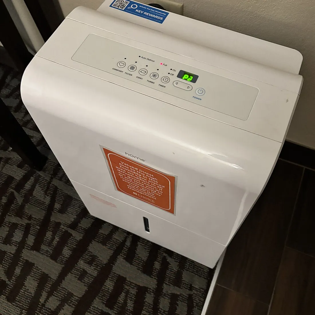 Portable dehumidifier standing on the floor of a hotel bedroom