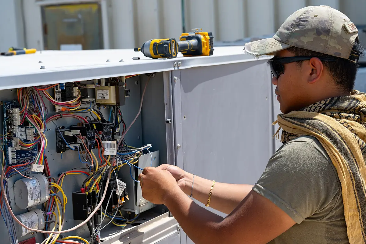 HVAC technician inspecting the inside of an outdoor unit