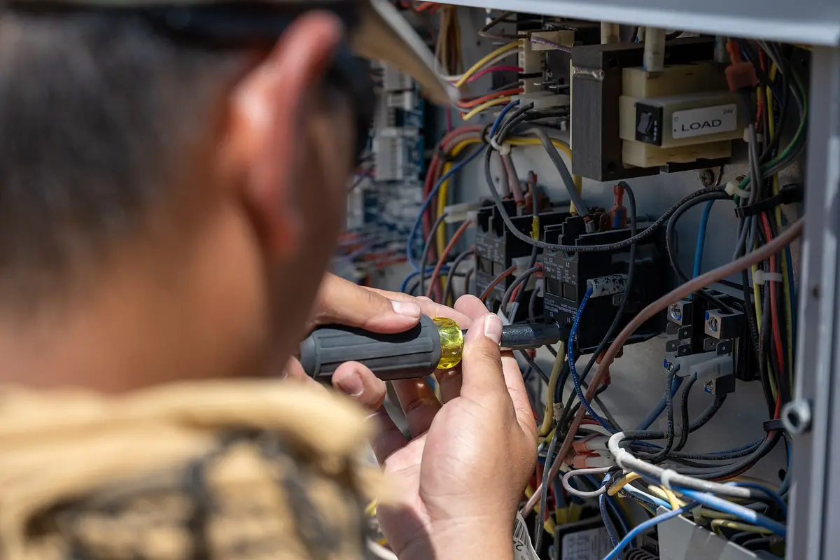 HVAC technician working on the wiring inside an AC unit