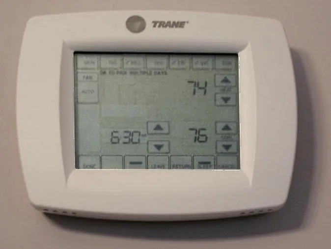 Touchscreen programmable thermostat in programming mode showing a 6:30 schedule period with heat and cool set points